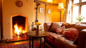 A cozy living room with a fireplace, leather sofa, and a table with a vase of flowers. - Quirky little Bolt-Hole, bags of character by a Historic Town with lovely walks (Hadleigh)