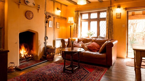 A cozy living room with a fireplace, leather sofa, and a wooden table. - Quirky little Bolt-Hole, bags of character by a Historic Town with lovely walks (Hadleigh)