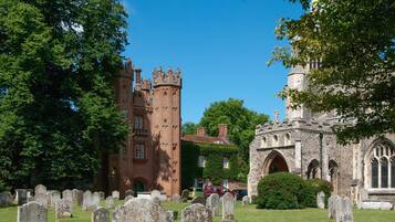 A historic building with a prominent tower and arched windows, surrounded by a cemetery with headstones.
