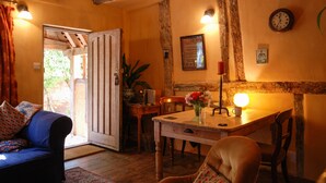 A cozy room with a wooden ceiling, a dining table with chairs, a sofa, and a door leading outside. - Quirky little Bolt-Hole, bags of character by a Historic Town with lovely walks (Hadleigh)