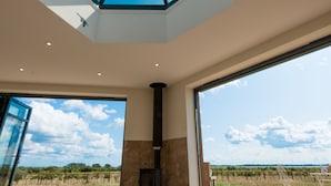 Ein modernes Interieur mit Oberlichter, großen Fenstern und Blick auf einen Weinberg.