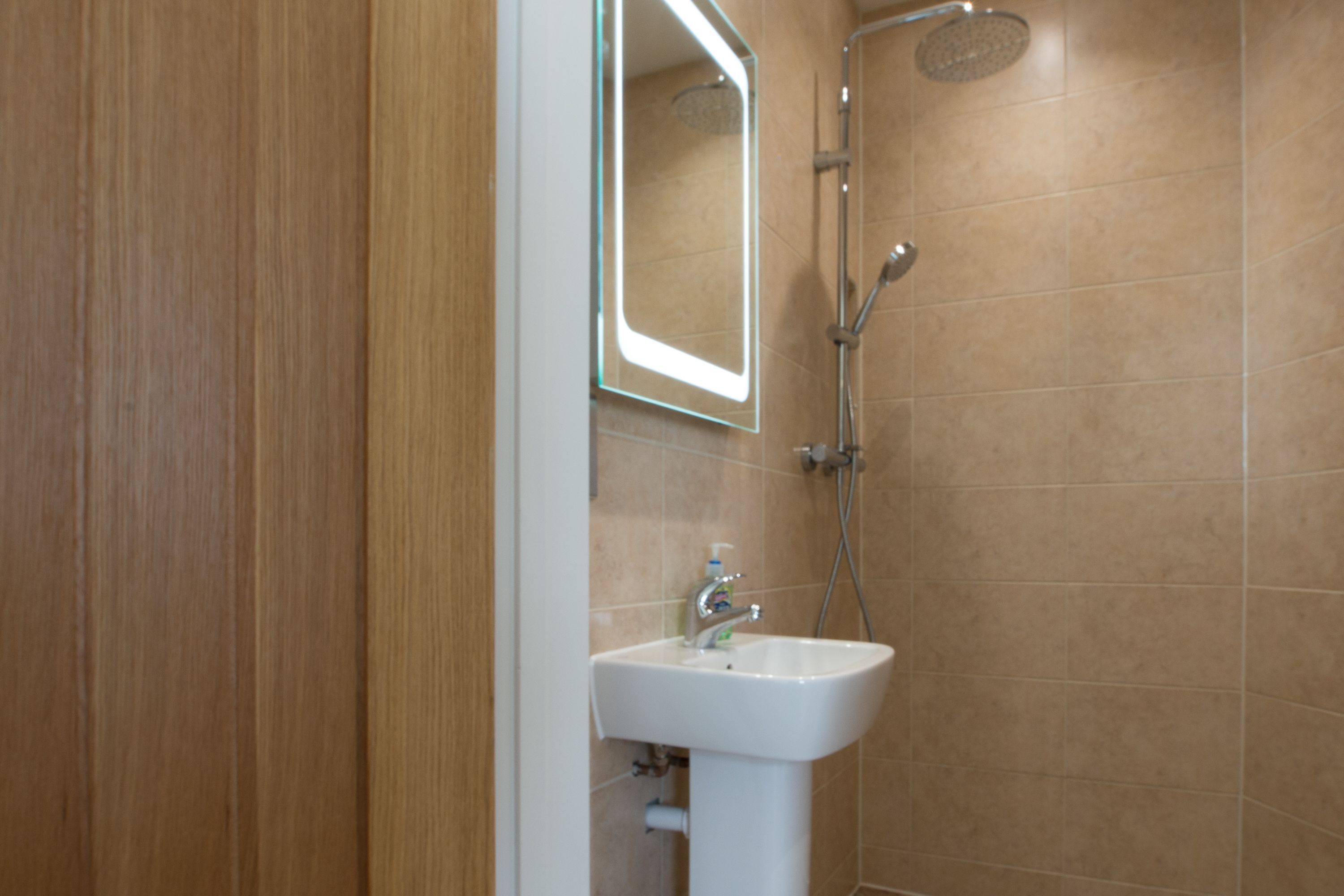 Un baño con un lavamanos blanco, un espejo y una ducha.