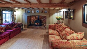 A cozy living room with a fireplace, wooden beams, and two sofas.