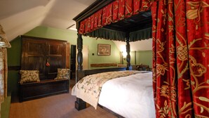 A bedroom with a four-poster bed, a wooden bench, and a green wall.