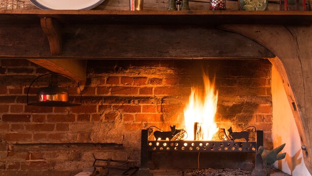 Une cheminée avec un feu qui crépite à l’intérieur, entourée d’un mur de briques.