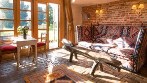 A rustic room with a patterned sofa, a wooden bench, a table with a vase, and a brick wall. - Dons Barn - A romantic holiday cottage with beautiful, beamed interiors. Wow. (Edwardstone)