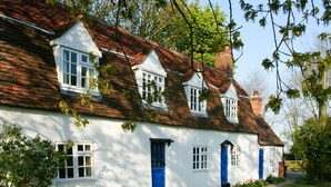 A white cottage with a red-tiled roof, multiple windows, and a blue door. - Remote, Comfort, Sea Views, and the romance of the beautiful Essex Marshes - The Wobbin (Tollesbury)