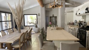 A modern kitchen with a large island, wooden chairs, and a dining table. - Beautiful contemporary villa, swimming pool and large garden (Berre-l'Étang)
