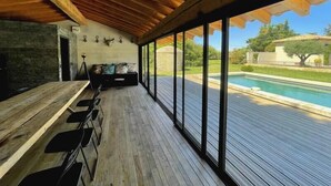 A covered outdoor area with a pool, wooden deck, and seating. - Beautiful contemporary villa, swimming pool and large garden (Berre-l'Étang)
