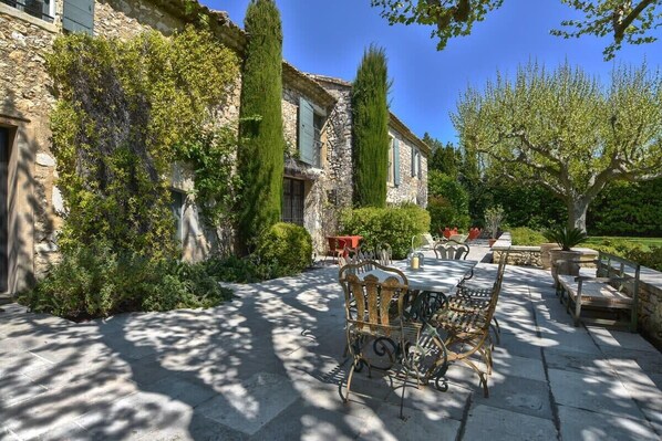 A stone building with ivy-covered walls, outdoor seating, and a garden.