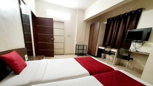 Ein Hotelzimmer mit zwei Betten, einem Schrank, einem Schreibtisch, einem Stuhl und einem Fernseher.