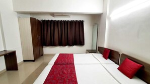Ein Hotelzimmer mit Bett, Kleiderschrank, Spiegel und einem Fenster mit Vorhängen.