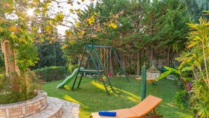 Un jardín con un columpio, una hamaca y una silla de descanso.