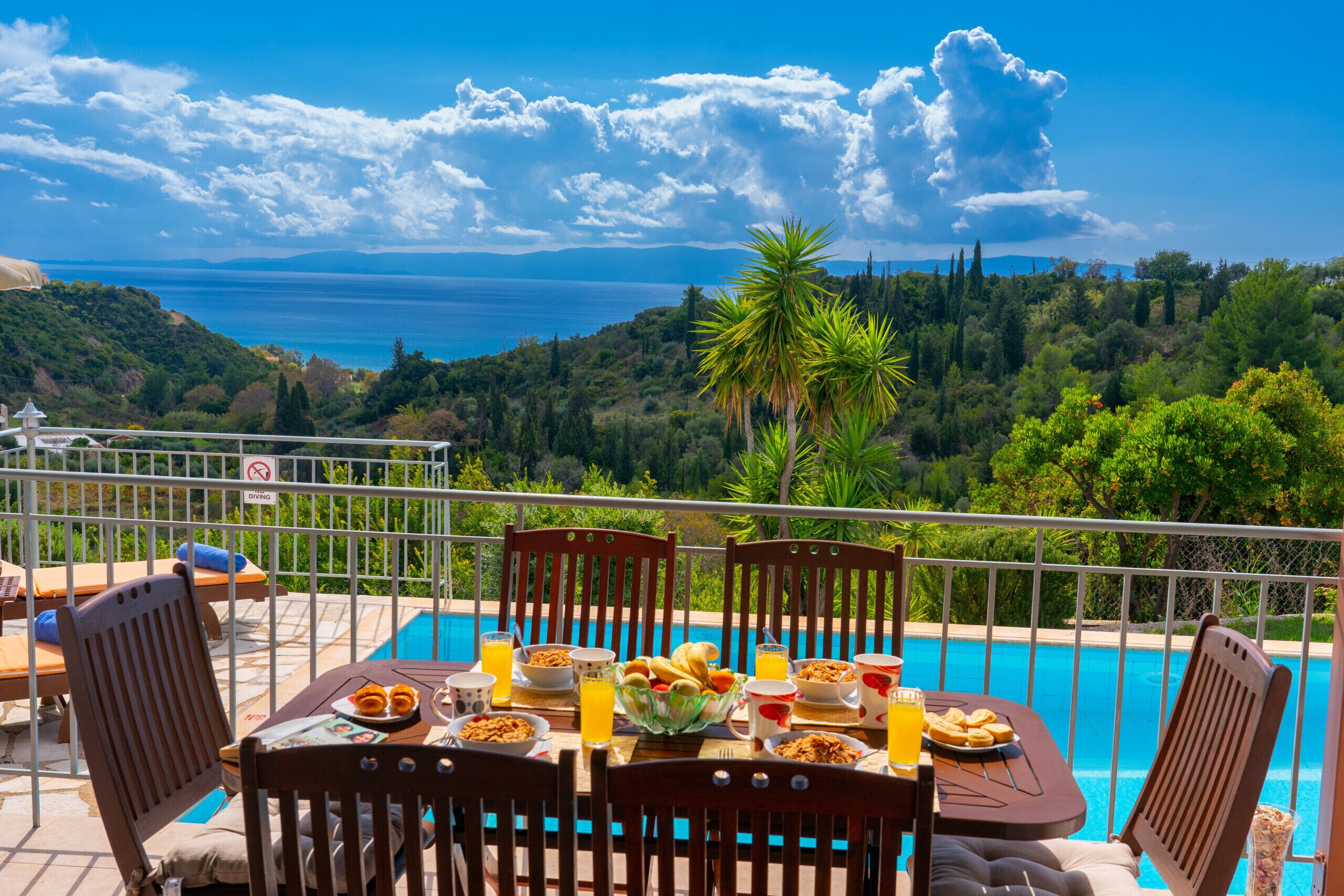 A dining table with breakfast items and a view of the sea.