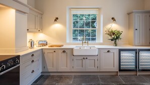 A kitchen with a built-in oven, a sink, and a window with a view of trees.