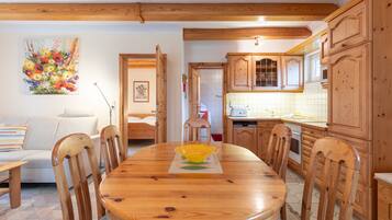 Ein Holztisch mit Stühlen, eine Küche mit Holzschränken und ein Bild an der Wand.