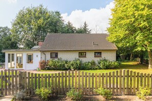 A house with a tiled roof, a small attached garage, and a wooden fence.