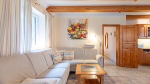 A cozy living room with a sofa, a glass-top coffee table, and a colorful floral painting on the wall. - Vacation home Heidehaus for up to 6 people (Enge-Sande)