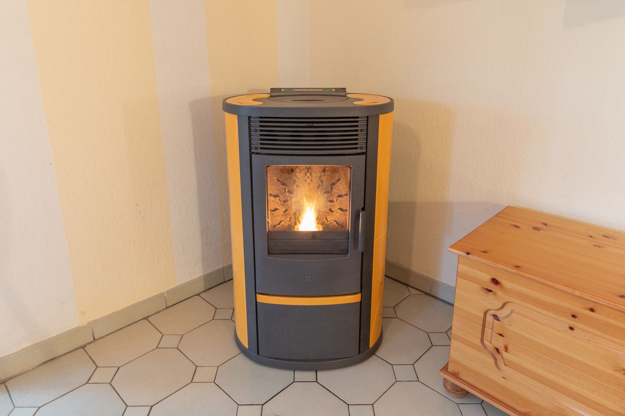 A wood-burning stove with a glass door, placed on hexagonal tiles.