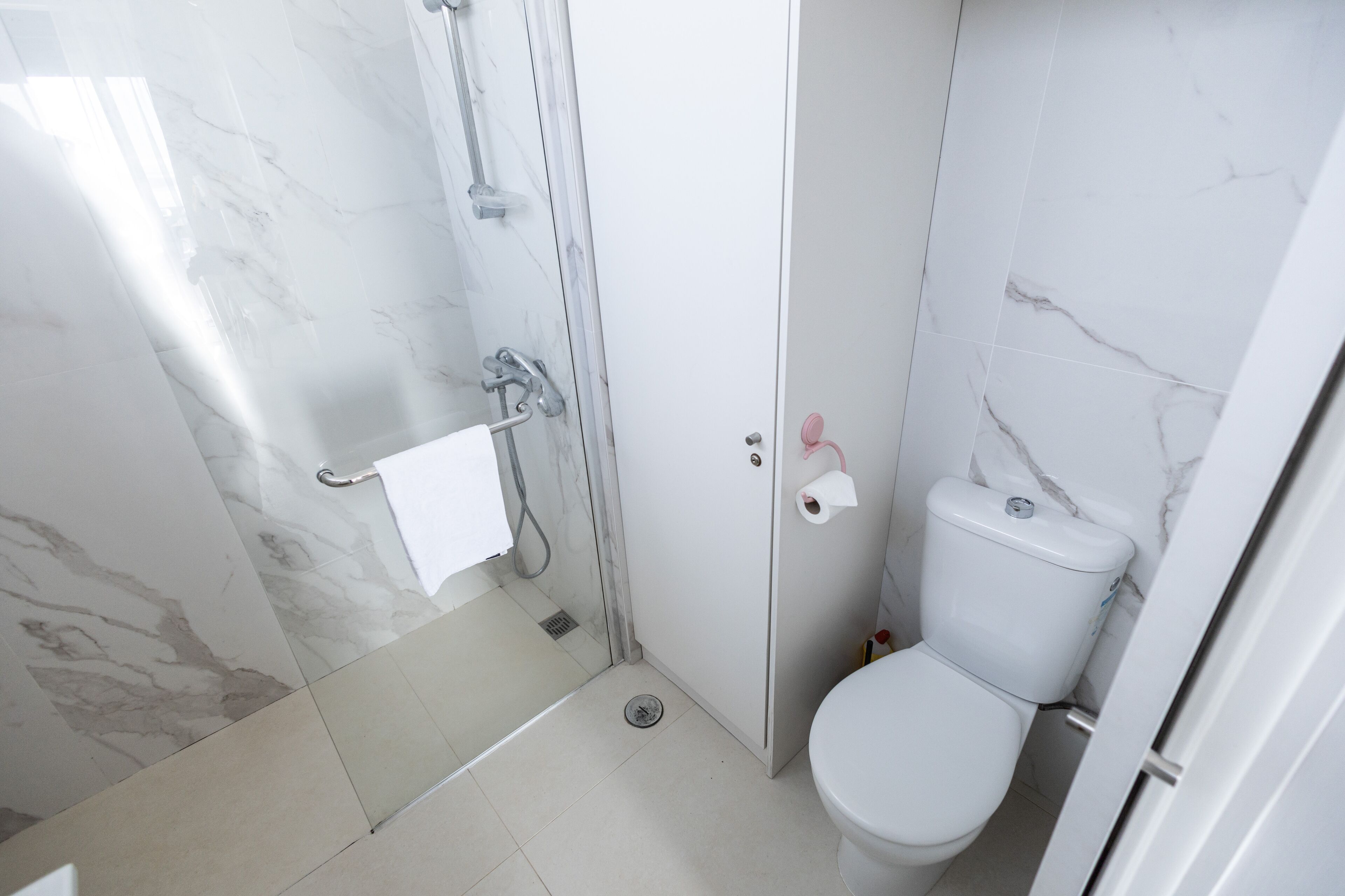 A bathroom with a shower, toilet, and a towel rack.