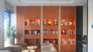 A modern lobby with a large bookshelf, comfortable seating, and a piano. - City Comfort Inn (Guangzhou)