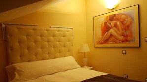 A hotel room with a tufted headboard, a bed with white linens, a painting on the wall, and a bedside lamp. - Luxury penthouse in the centre of Lerma (Lerma)
