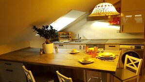 A modern kitchen with a wooden island, white chairs, and a hanging light fixture. - Luxury penthouse in the centre of Lerma (Lerma)