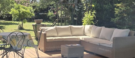 An outdoor patio with a cushioned sofa, a small table, and chairs.