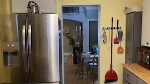 A kitchen with a stainless steel refrigerator, a dining area with a table and chairs, and a hallway leading to another room. - Built in 1866 this hillside home is close to everything! (Duluth)