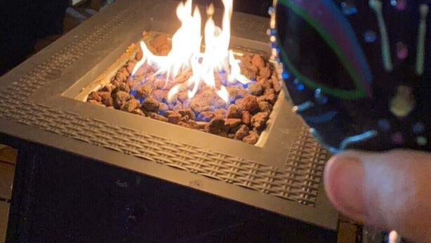 A fire pit with flames, surrounded by outdoor furniture and string lights. - Built in 1866 this hillside home is close to everything! (Duluth)
