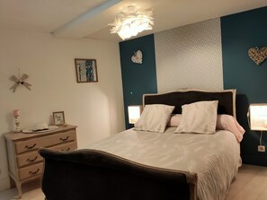 A bedroom with a bed, bedside tables, a dresser, and decorative items.