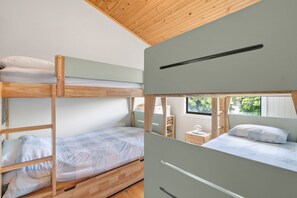 A bunk bed room with a wooden ceiling, a window, and a bedside table with a lamp. - Shell Shack (Apollo Bay)