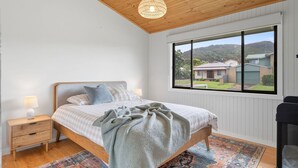 A bedroom with a bed, bedside lamps, a window with a view, and a ceiling light fixture.