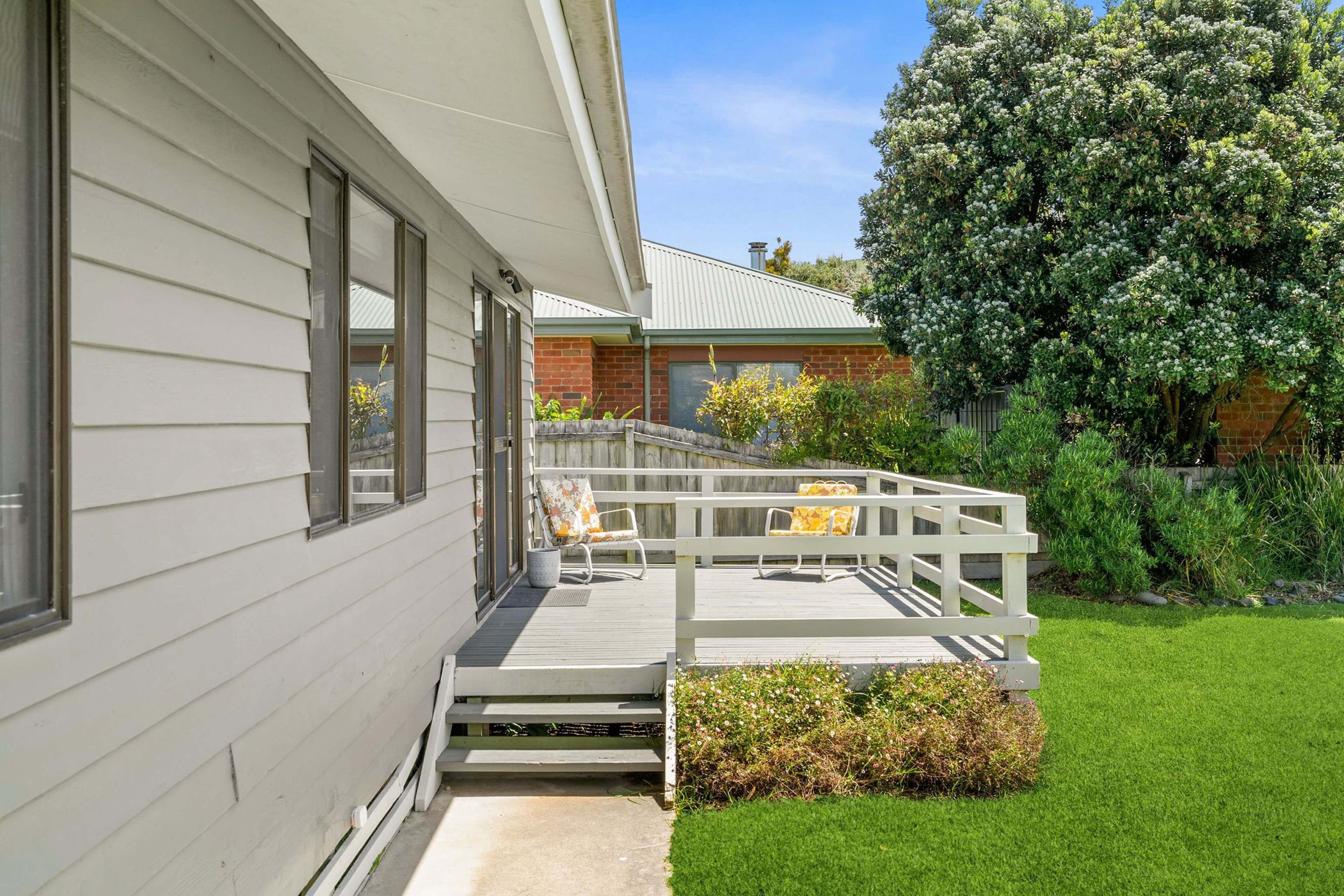 A residential property with a covered porch, a brick extension, and a well-maintained lawn.