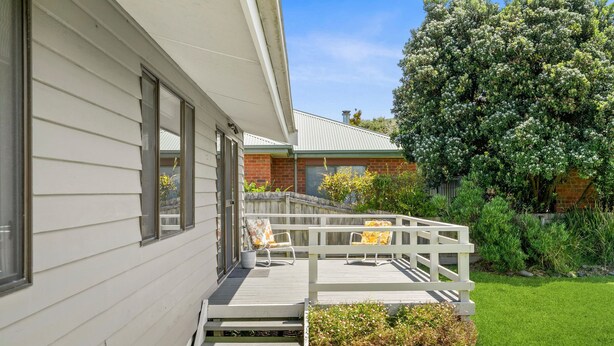 A residential property with a covered porch, a brick extension, and a well-maintained lawn.