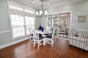 A dining area with a round table, white chairs, and a chandelier. - 10% off 3-7 thru Aug. 4BR home. Short walk to beach. 3 night minimum all year. (North Myrtle Beach)