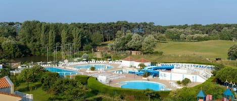 A resort with multiple swimming pools, a children's play area, and lush greenery.