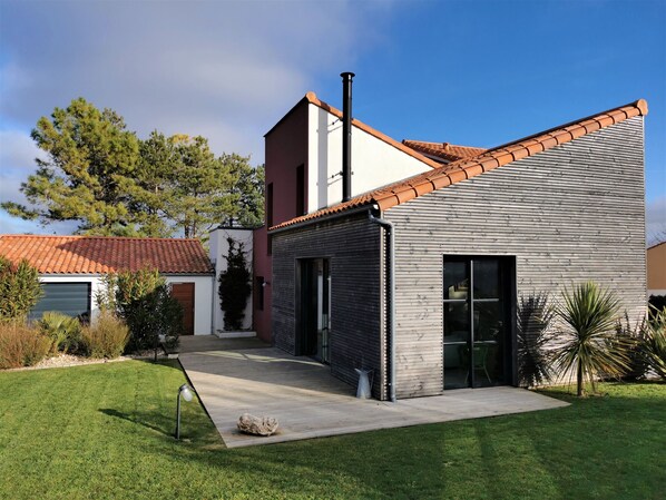 A modern house with a tiled roof, a garage, and a well-maintained lawn.