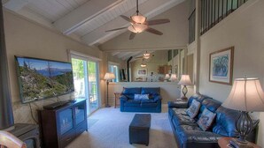 A spacious living room with a fireplace, a large TV, and a cozy seating area with a sofa and ottoman. - Park View Paradise | BBQ | Summer Pool & Tennis (Tahoe City)