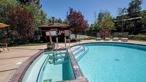 A swimming pool with a lifeguard station, surrounded by trees and a fenced area with lounge chairs. - Park View Paradise | BBQ | Summer Pool & Tennis (Tahoe City)