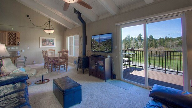 A spacious living room with a ceiling fan, a fireplace, a television, and a balcony with a view of the outdoors. - Park View Paradise | BBQ | Summer Pool & Tennis (Tahoe City)