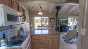A kitchen with granite countertops, wooden cabinets, a built-in microwave, and a dining area with a table and chairs. - Park View Paradise | BBQ | Summer Pool & Tennis (Tahoe City)