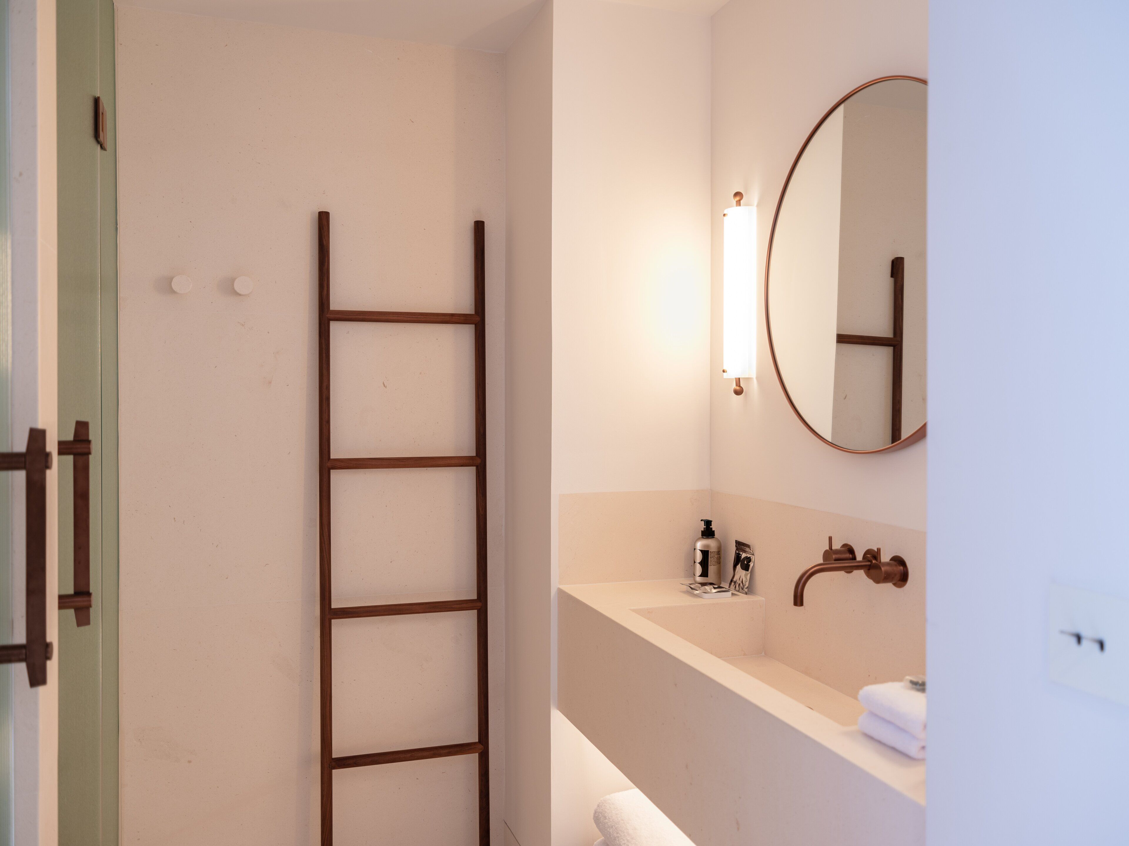 A bathroom with a wooden ladder, a sink, a mirror, and a towel rack.