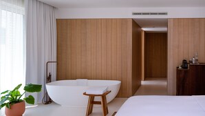A modern hotel room with a large white bathtub, a wooden vanity, and a large bed. - The Standard, Ibiza (Ibiza Town)