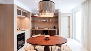 A modern kitchen with a round dining table, built-in shelves, and a central chandelier.