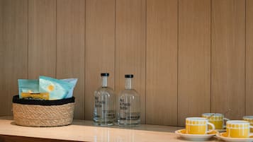 Una estantería de madera con vasos transparentes, platos y una cesta que contiene una botella y una bolsa.
