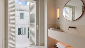 A modern bathroom with a large mirror, a sink, and a towel rack.