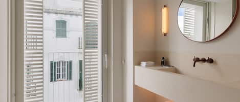 A modern bathroom with a large mirror, a sink, and a towel rack.
