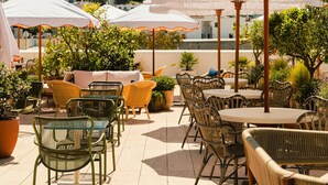 Una terrazza esterna con mobili in vimini, ombrelloni bianchi e lampadine pendenti.