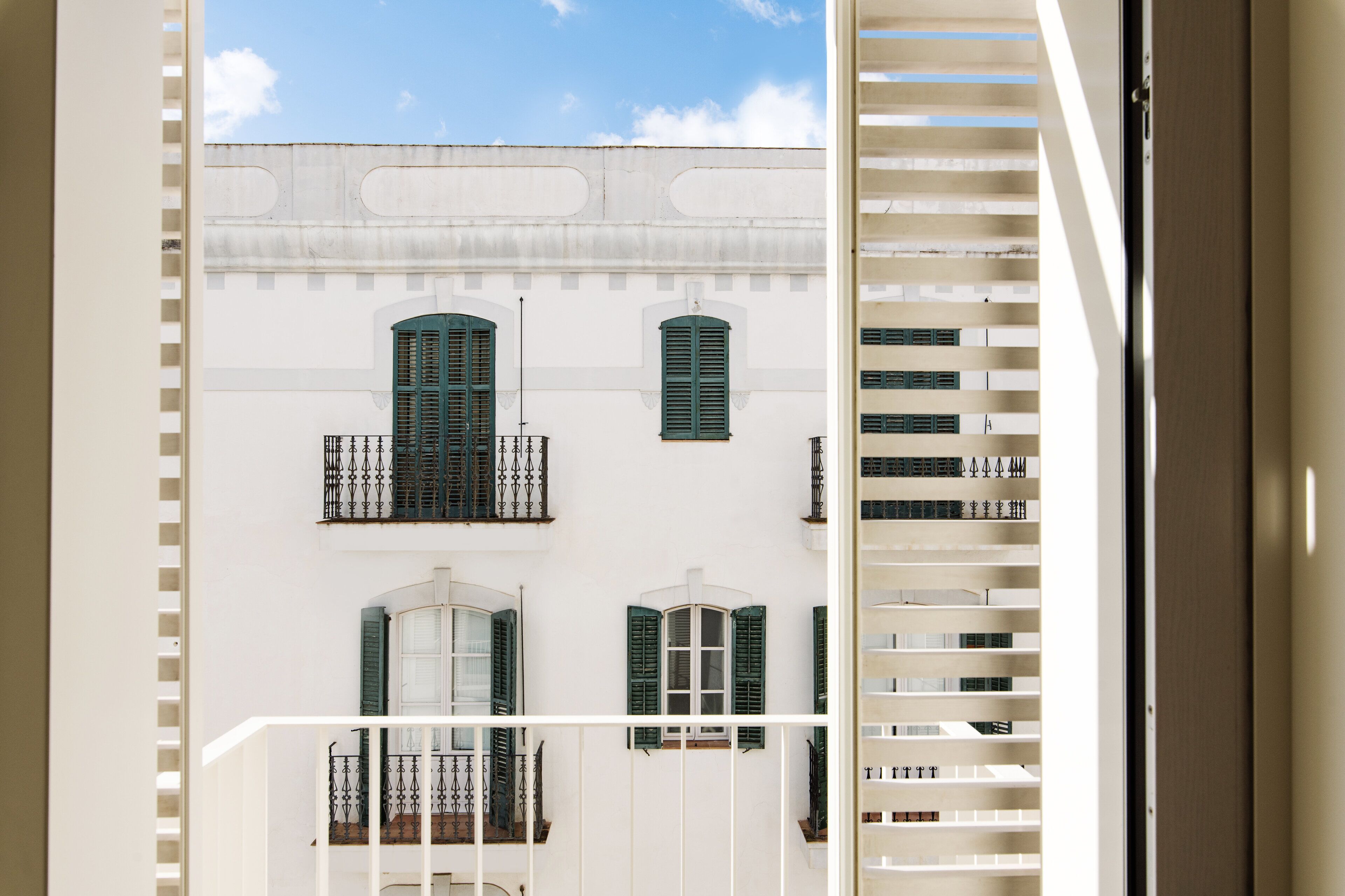 A white building with green shutters and balconies.